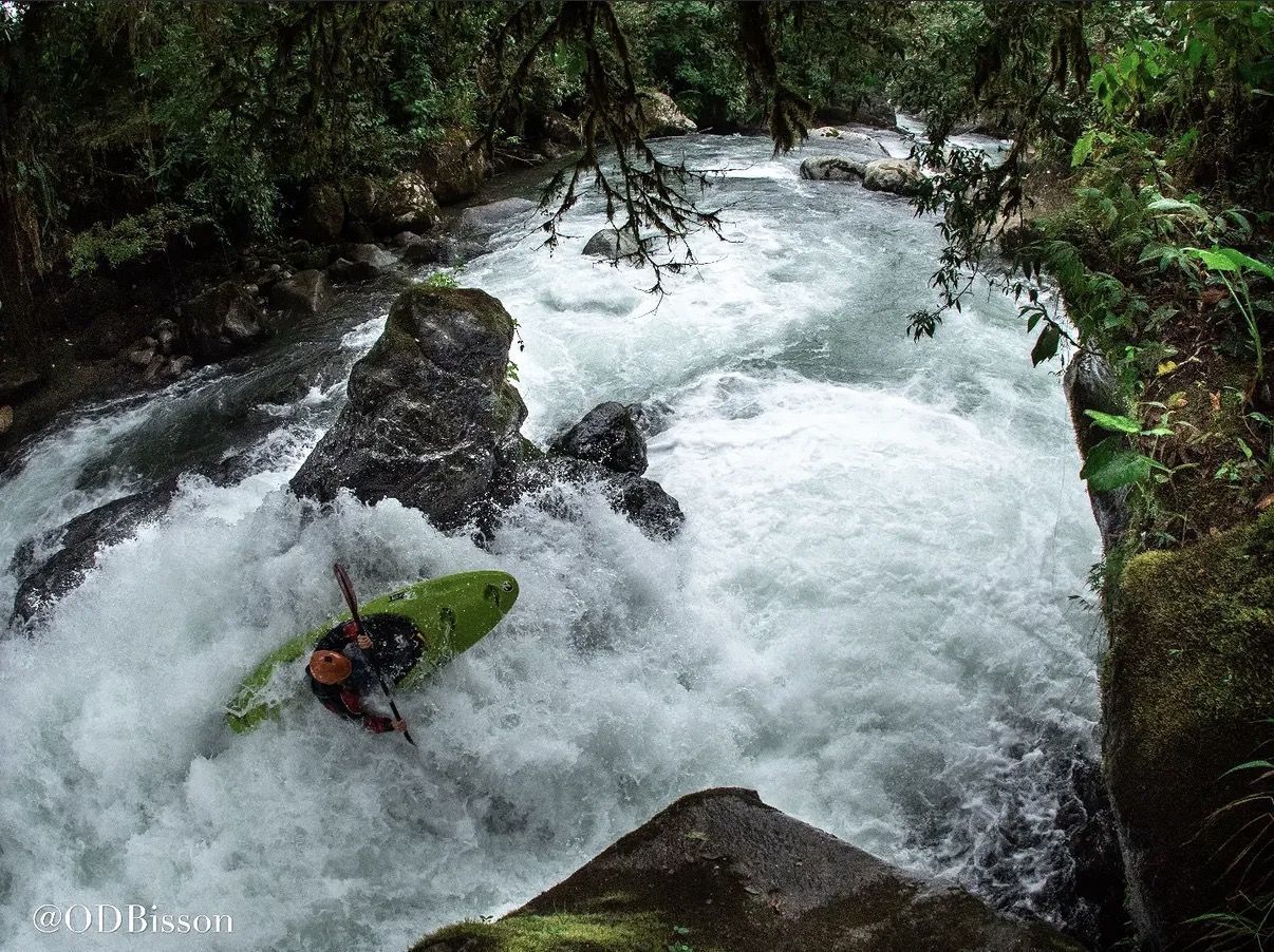 Seen from above, a kayaker in a green boat drives through a big hole