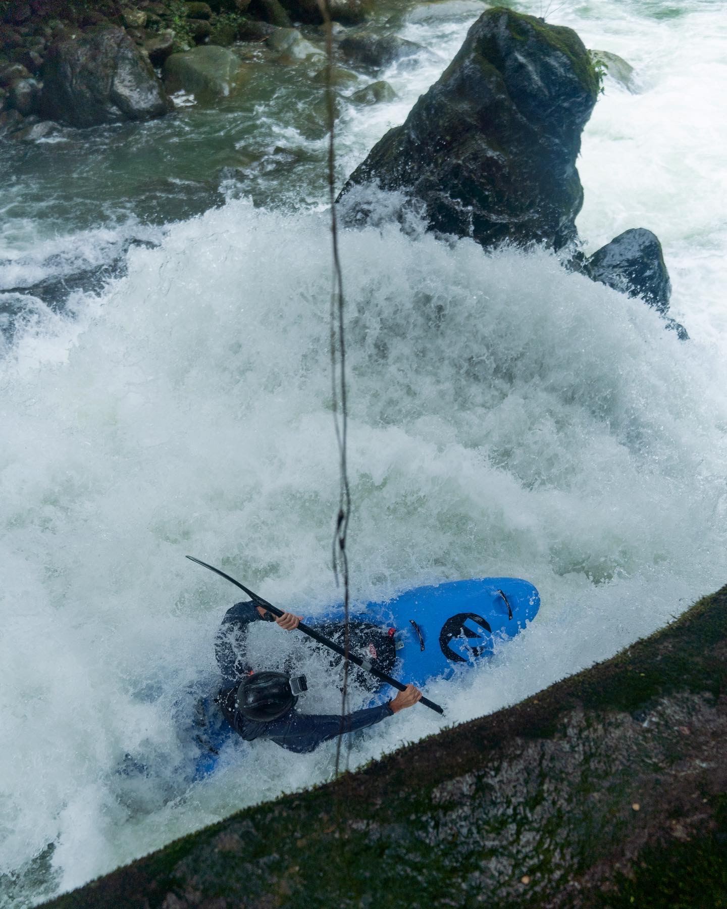 Seen from above, a kayaker punches through a wall of whitewater